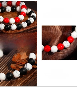 Detail of 8mm matte black, white turquoise, and red bead bracelet on wood background