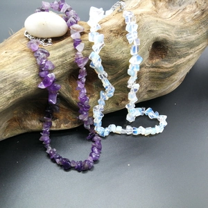 Macro shot of natural amethyst and moonstone chip necklaces on rustic wood and white pebbles
