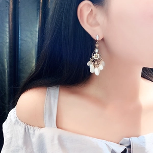Detail of vintage gold tassel earrings with white teardrop crystals on model