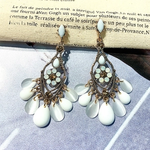 Retro crystal tassel earrings with opal stones and rhinestones on vintage script background