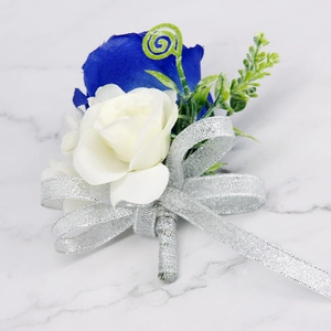 Detail van koningsblauwe en crème roos corsage met zilveren lint op marmeren achtergrond