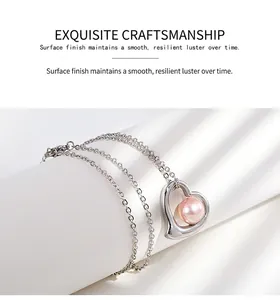 Close-up of heart-shaped stainless steel pendant with pink pearl on silver chain