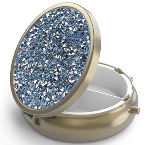 Macro shot of circular gold metal pill box with blue rhinestones and two inner compartments