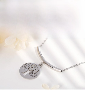 Close-up of silver tree of life pendant with polished curved tube on a minimalist chain