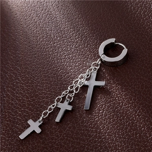 Detail of silver titanium steel earrings with triple cross pendants on leather texture