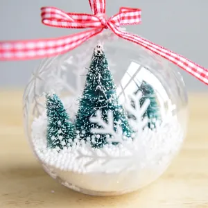 Transparent Christmas bauble with miniature pine trees and fake snow inside
