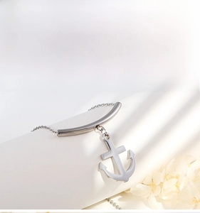 Detail shot of silver anchor necklace on geometric props with white floral accents