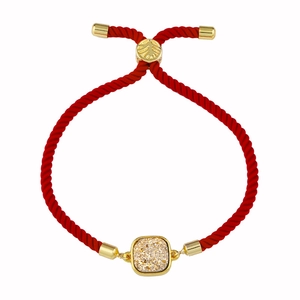 Détail du bracelet en corde tressée rouge avec centre en cristal doré et perle texturée
