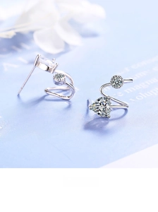 Macro detail of S-curve silver earrings with heart-shaped sparkling cubic zirconia stones