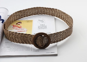 Gros plan sur la texture de la ceinture tressée marron et la boucle ronde en bois