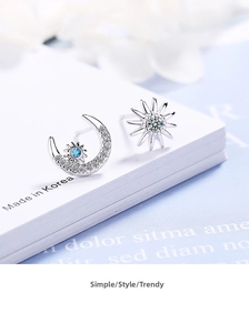 Detail of asymmetric moon and star stud earrings with blue and white inlaid crystals