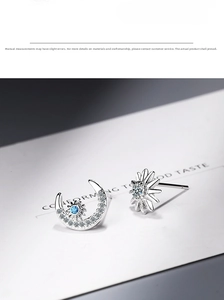 Detail of asymmetric sun and moon stud earrings with blue and white crystals on card