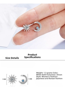 Close-up of asymmetric sun and moon stud earrings featuring blue and white zircons