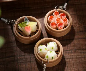 Detailed view of realistic miniature food keychains with bamboo steamers on wooden surface