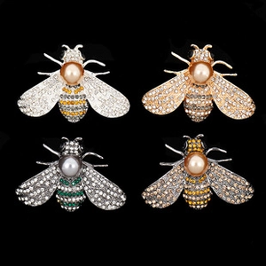 Macro detail of bee brooches in four colors with pearls and sparkling rhinestones