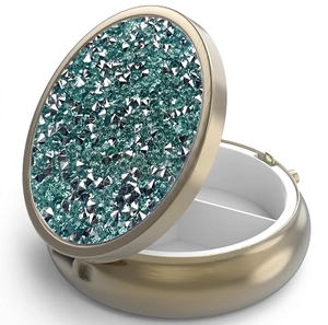 Detail of round gold pill box with sparkling green crystals and two compartments