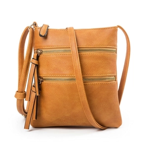Detailed view of ginger yellow crossbody bag with multiple zippers and faux leather texture