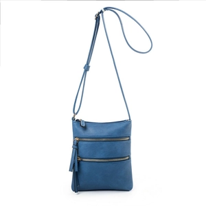 Detail view of blue PU leather crossbody bag featuring three-layer zipper pockets and tassel