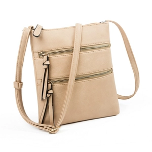 Detail view of beige crossbody bag showing multi-zipper pockets and stylish tassel decor