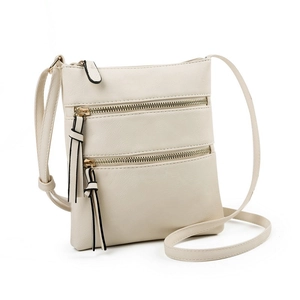 Detail of cream white faux leather bag with three parallel metal zipper pockets and tassels