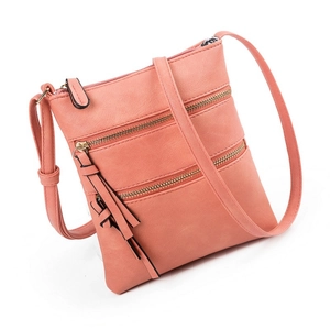 Detail of pink crossbody bag with multiple zip pockets and long tassel zipper pulls