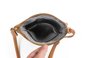Interior view of brown leather crossbody bag featuring black and white striped lining