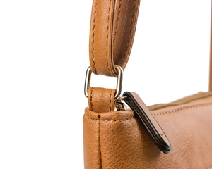 Detail of brown leather bag showing gold D-ring and zipper pull with premium stitching