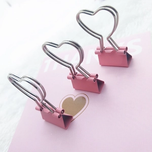 Close-up of three pink heart-shaped metal binder clips on a decorative pink card
