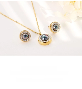 Close-up of golden necklace and stud earrings set with grey pearls and pavé crystals