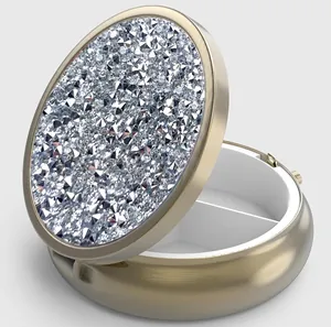 Detail view of gold pill box showing white three-compartment interior and rhinestone lid