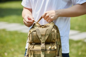 Detailed view of sand-colored tactical backpack with MOLLE system and reinforced buckle