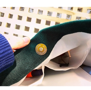 Detail of the magnetic closure on a green corduroy tote bag showing interior lining