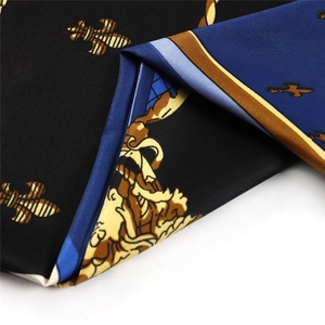 Détail du foulard en soie montrant des motifs de fleurs de lys et des volutes baroques