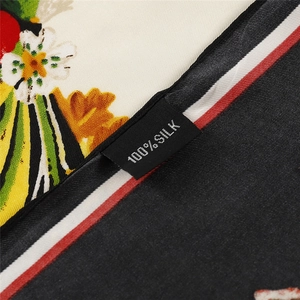Silk scarf with butterfly floral print showing 100% silk material label on edge