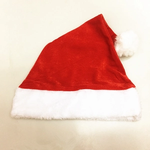 Detailed close-up of soft red velvet Christmas hat with fluffy white plush ball