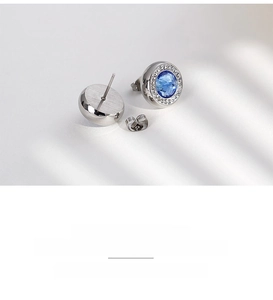 Macro detail of round blue crystal stud earrings with micro-inlaid diamonds in steel
