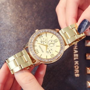 Golden metal ladies watch with rhinestone bezel and decorative sub-dials on a wrist