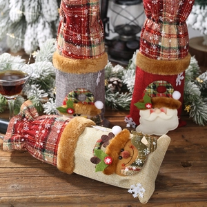 Three linen Christmas wine bottle bags with Santa and snowman on a festive table