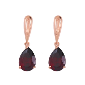 Dettaglio di orecchini in oro rosa con pietre di granato rosso con taglio a goccia