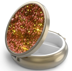 Close-up of golden pill box with sparkling orange crystals and two internal compartments