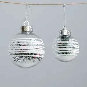 Clear Christmas balls with white stripes, pine needles, red berries and artificial snow
