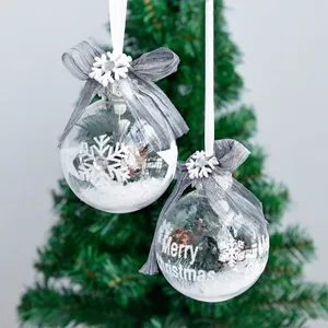 Two 6cm clear Christmas balls with snow, pinecones and mesh bows on tree branches
