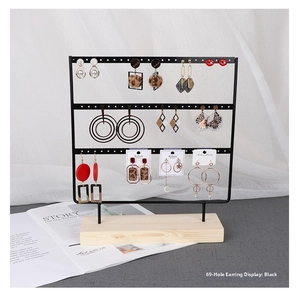 Detailed macro view of black metal 69-hole jewelry rack with solid wood base