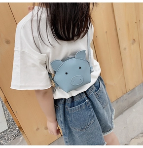 Kid's blue cartoon pig shoulder bag worn by child with metal zipper and cute charm detail