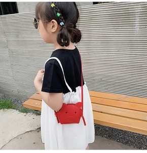 Cute red pig cartoon kids crossbody bag shown on a little girl in an outdoor setting