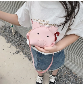 Pink cartoon pig shoulder bag for kids made of PU leather shown on a child model