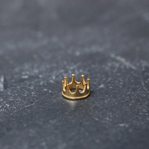 Macro shot of 3D gold crown spacer bead for DIY jewelry making on dark stone texture