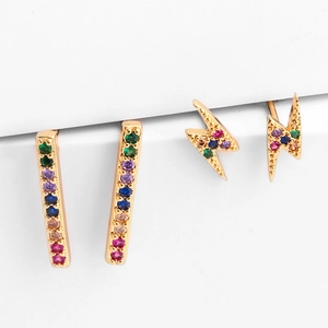 Detail of gold stud earrings set featuring rainbow zircon lightning and bar shapes