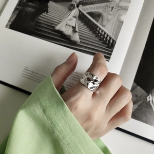 Close-up of irregular lava texture silver ring worn on index finger with artistic aesthetic