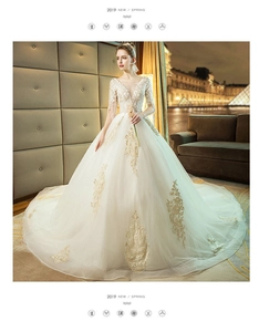 Exquisite gold floral embroidery detail on a white ball gown wedding dress with lace sleeves